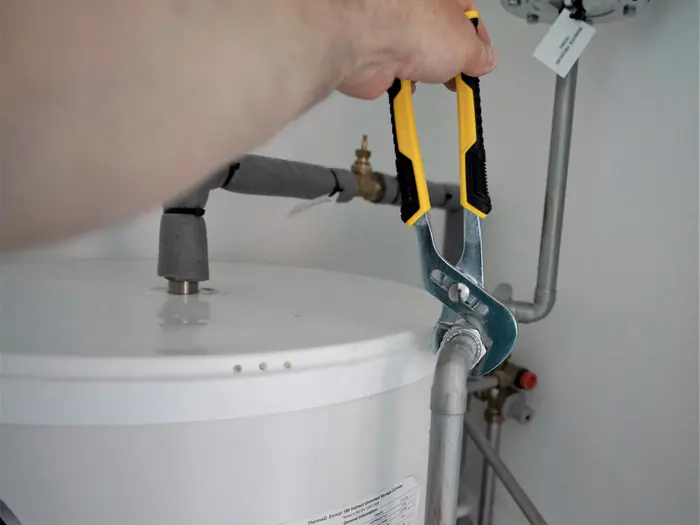 Plumber tightening a fitting on top of a water heater