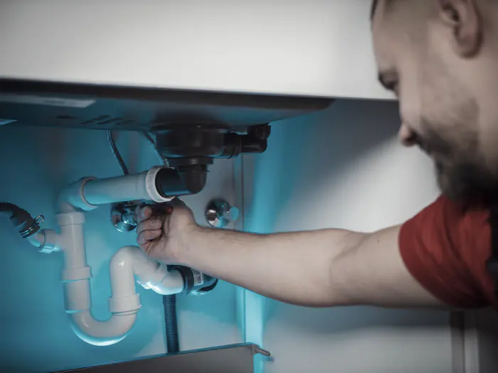 Plumber working on the drain under a sink